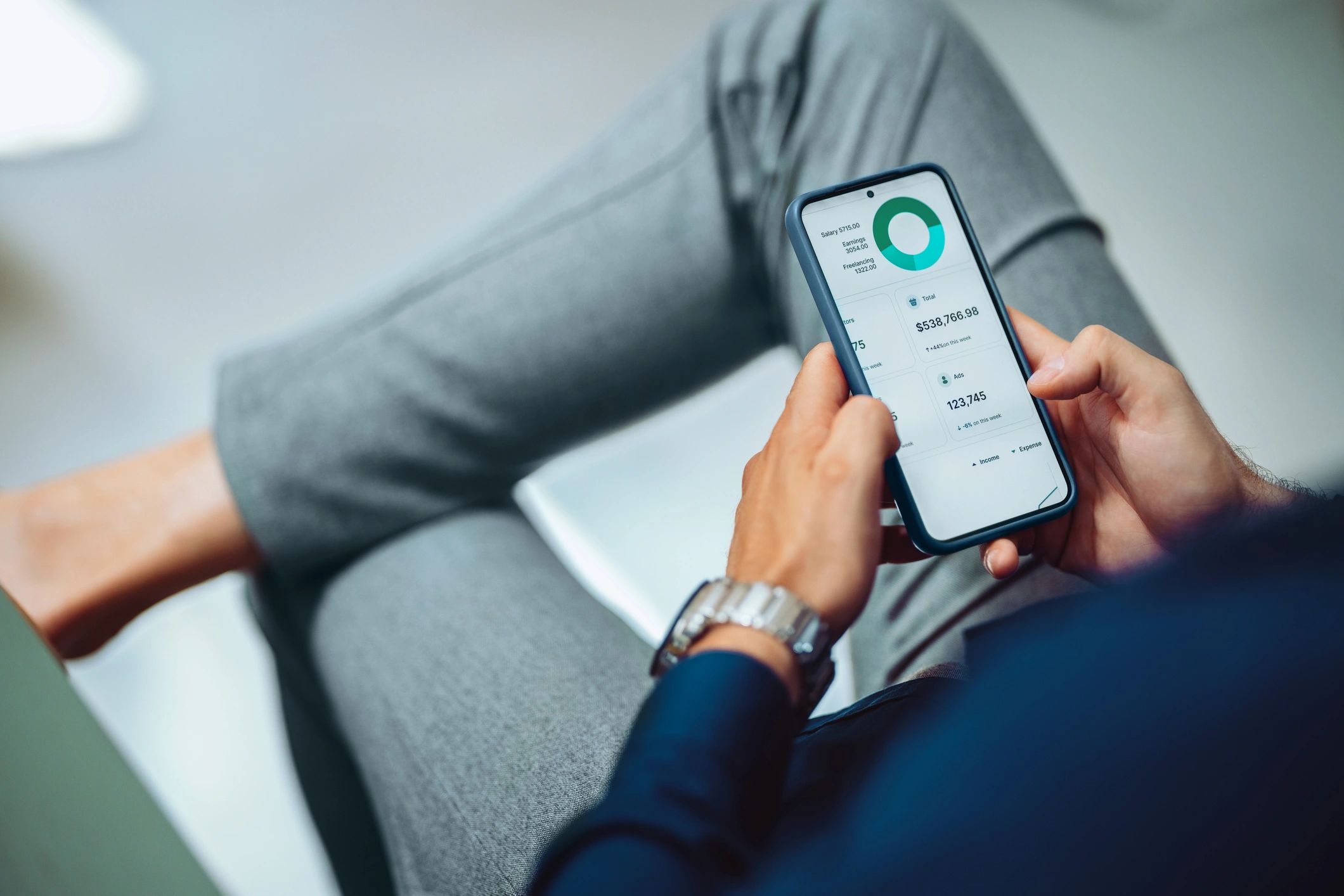 Professional reviewing data on a smartphone at a desk